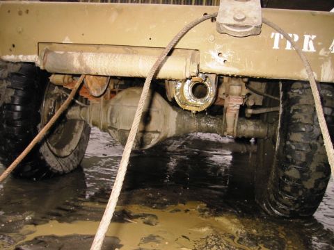 1985 Ford Bronco - Close-up view of the rear axle and suspension system of a large vehicle, with a tow cable attached.