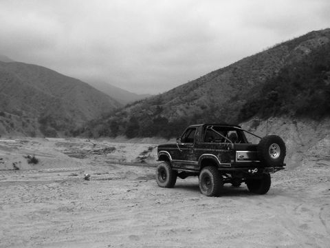 1985 Ford Bronco - A Ford Bronco is parked in a desolate, mountainous landscape, with a spare tire on the rear.