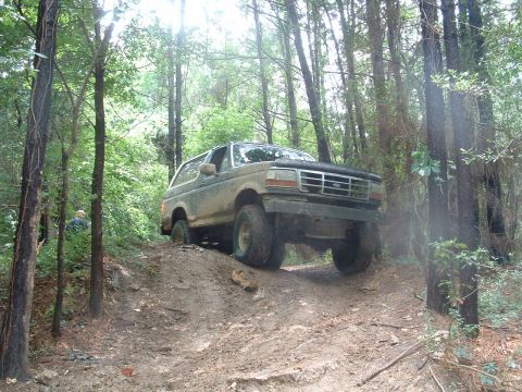 1993 Ford Bronco - A 1993 Ford Bronco navigates a muddy, wooded trail.