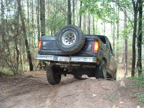 1993 Ford Bronco - Ford Bronco navigates a muddy off-road trail through a wooded area.