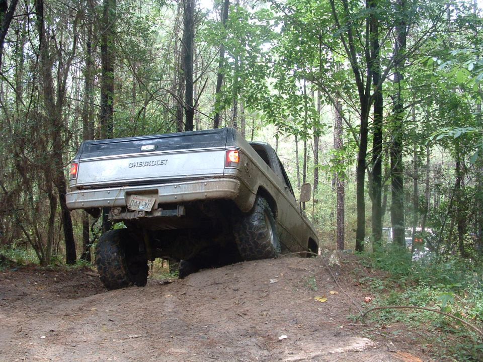 Chevrolet pickup truck on muddy hill, rear view, lifted suspension, off-road tires