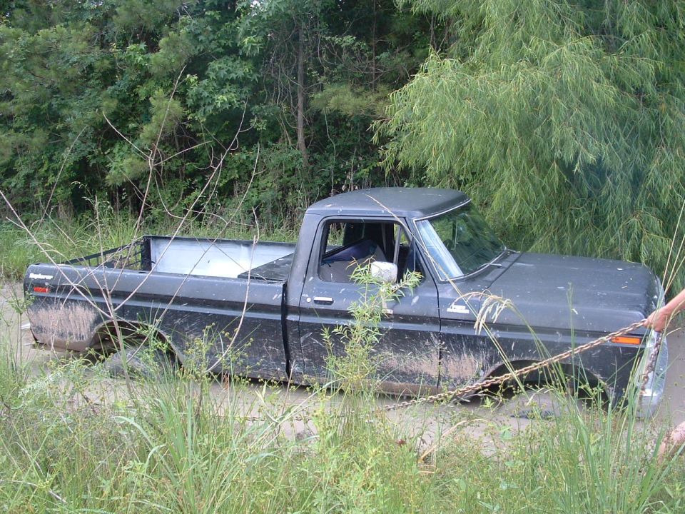 Dark pickup truck stuck in mud, 3/4 front view