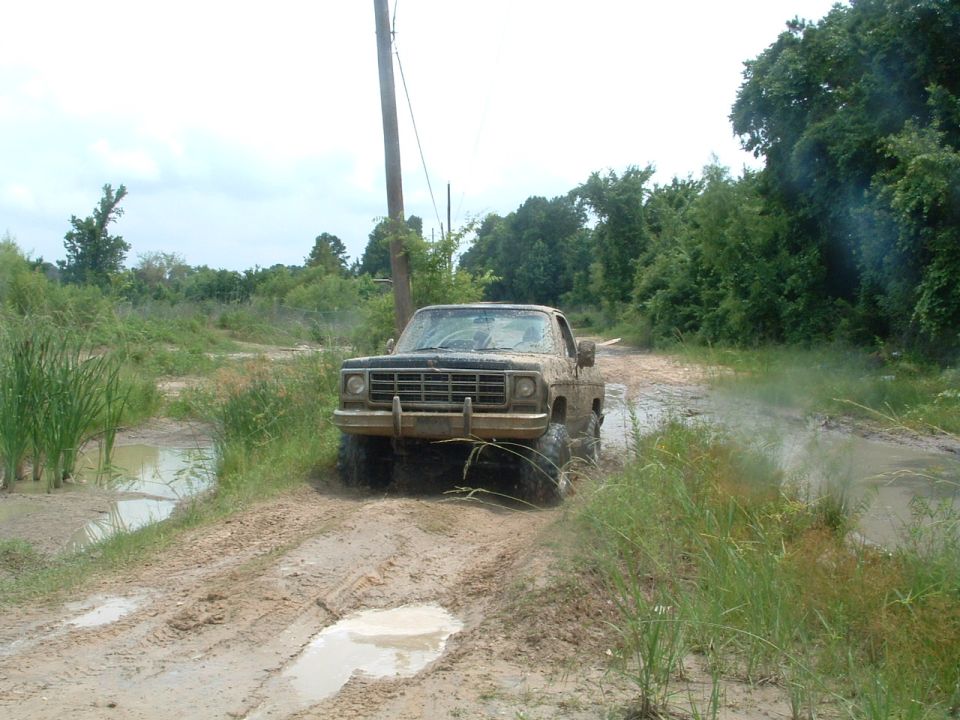 Pickup truck driving through mud and water. It has a square grille and prominent tires
