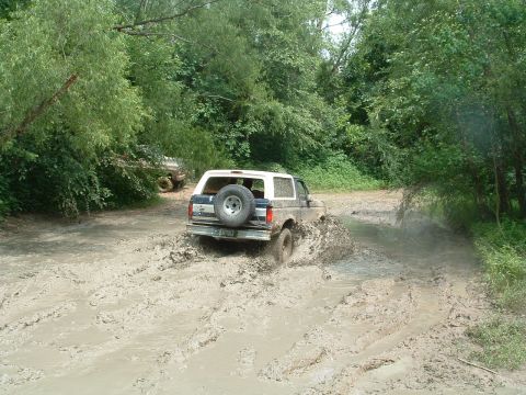 1993 Ford Bronco - A Ford Bronco navigates a challenging muddy off-road course.