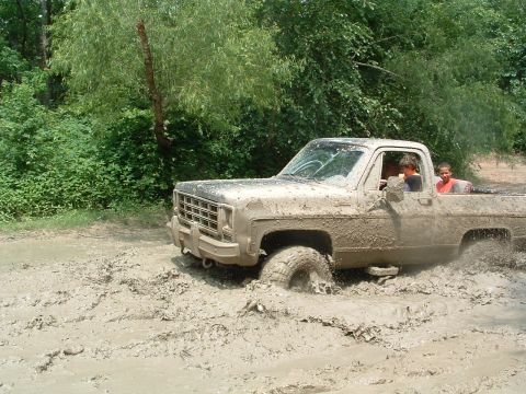 1993 Ford Bronco - A pickup truck navigates through a muddy terrain, with two occupants visible inside the cab.