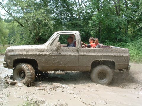 1993 Ford Bronco - This truck is covered in mud as it navigates through a challenging off-road course.