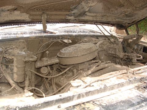 1993 Ford Bronco - The engine bay of a vehicle is heavily covered in mud, obscuring most details.