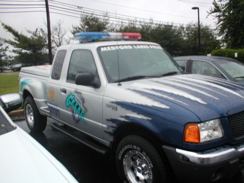 1979 Ford Bronco - A police truck with emergency lights is parked next to another vehicle.