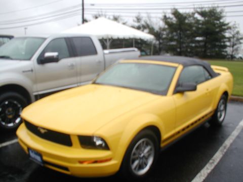 1979 Ford Bronco - Yellow convertible Mustang parked next to a silver pickup truck under an overcast sky.