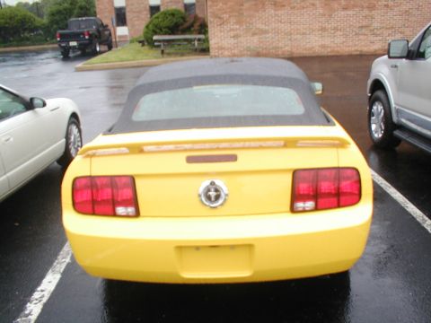 1979 Ford Bronco - A yellow convertible is parked in a lot, showing its rear end and taillights.
