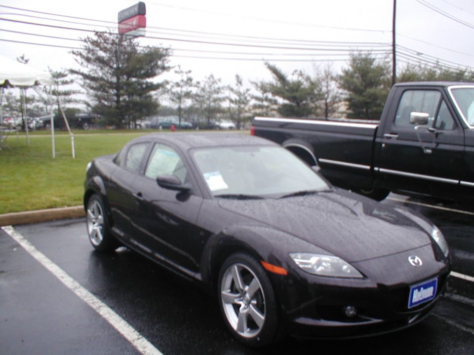 Dark colored Mazda RX-8 parked next to a black pickup truck