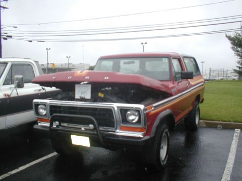 1979 Ford Bronco - A red 1979 Ford Bronco is parked outside with its hood open, next to a white truck.
