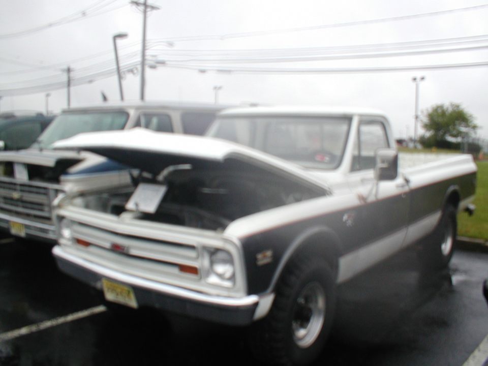 GMC pickup truck with hood open, parked next to another truck