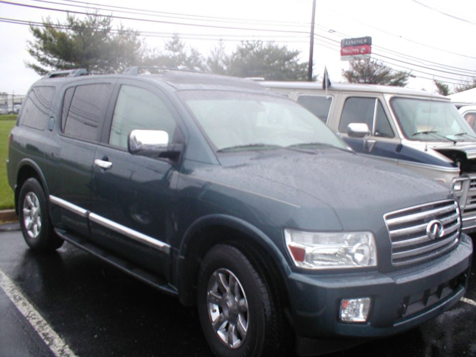 Dark green SUV parked on a wet asphalt lot, with a blue and white van behind it