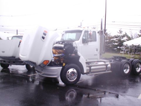 1979 Ford Bronco - A white semi-truck is parked with its hood open, revealing the engine compartment. Another truck is visible behind it.