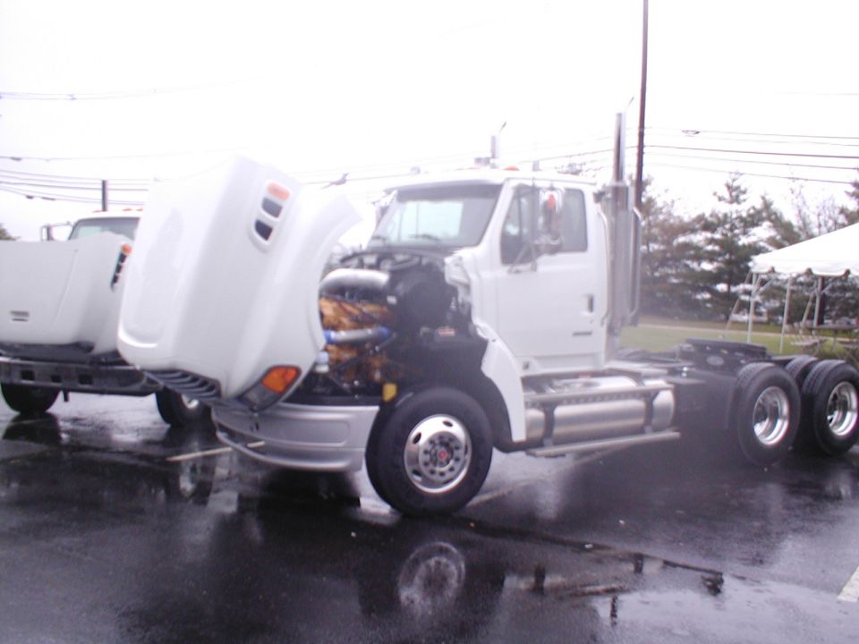 White semi-truck with hood up showing engine. Another semi is behind it
