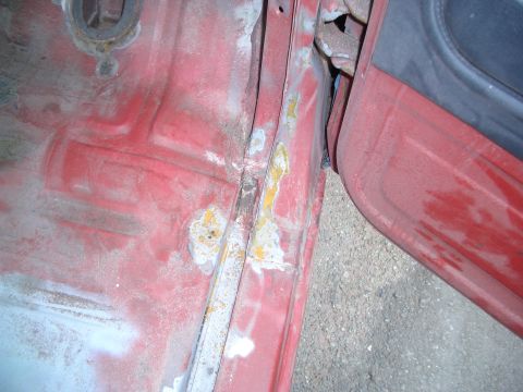 1981 Ford Bronco - Close-up view of the interior door jamb and floor pan, showing areas of rust and primer.