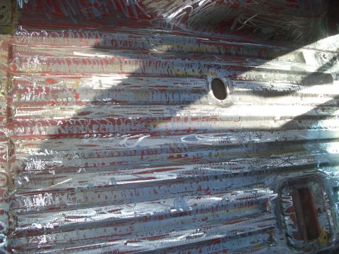 1981 Ford Bronco - The floor pan of a vehicle shows signs of rust and previous paint layers being removed.
