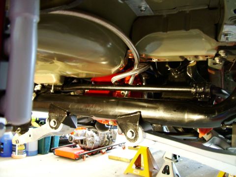 2003 Ford Mustang - Underbody view of a car, showing fuel tank, exhaust components, and a transmission on a dolly.