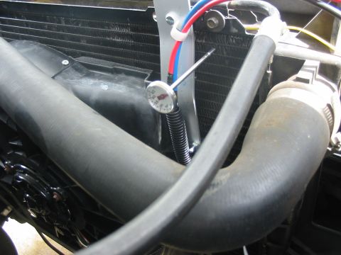 1993 Ford Bronco - Close-up of a vehicle's radiator and cooling fan assembly, a thermometer.
