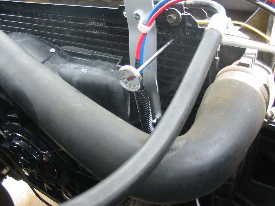 Radiator, fan, and hoses with a thermometer attached to the radiator fins