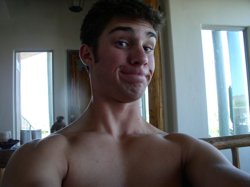 Man with a goofy expression, shoulders and upper chest visible. Watermark says SUPERMOTORS