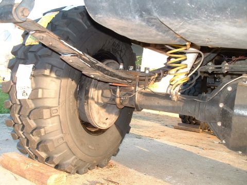 1995 Ford Bronco - Close-up view of the rear axle and suspension system of a vehicle, with a large tire visible.