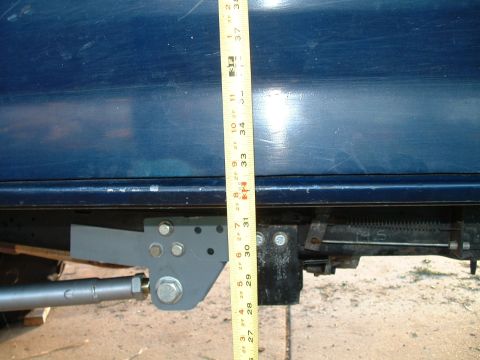 1995 Ford Bronco - Tape measure shows height of a modified suspension part on a blue vehicle.