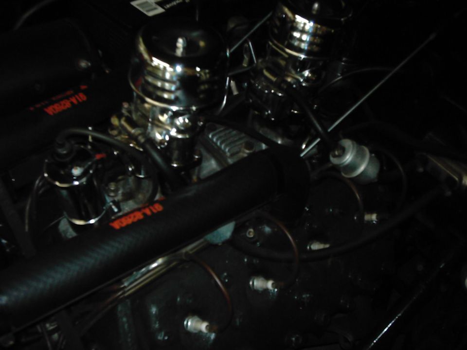 Engine bay with dual carburetors and chrome air cleaners. Black hoses and wiring are visible
