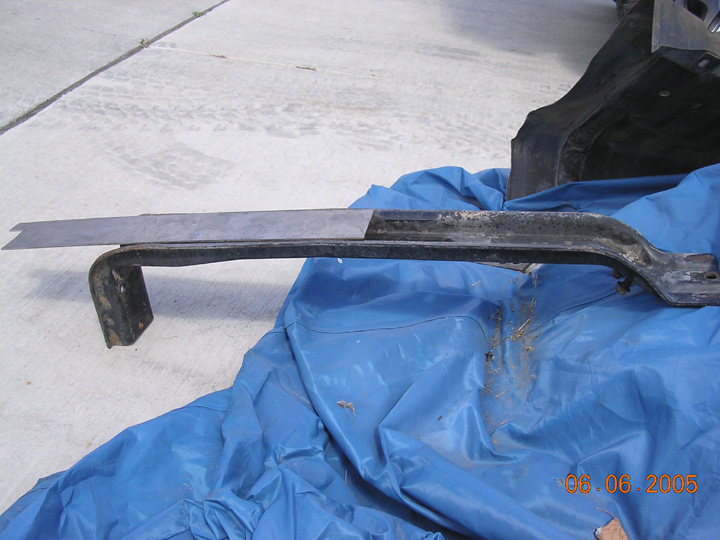Removed black steel frame crossmember on blue tarp with flat steel plate alongside