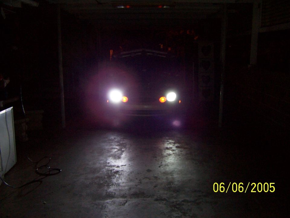 Car headlights illuminated in a dark garage, with a date stamp of 06/06/2005
