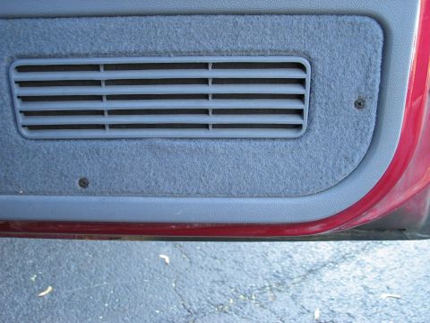 1995 Ford Bronco - Close-up of a vehicle's interior door panel, showing a gray carpeted section with a horizontal air vent.