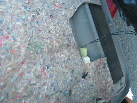 1995 Ford Bronco - The interior of a car door panel shows insulation and wiring, possibly for a window motor.