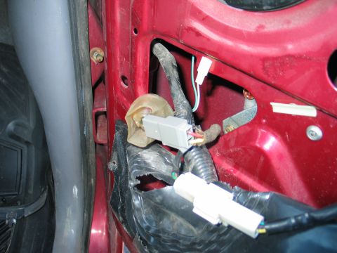 1995 Ford Bronco - Close-up of the window motor wiring harness and connectors within a red vehicle door panel.