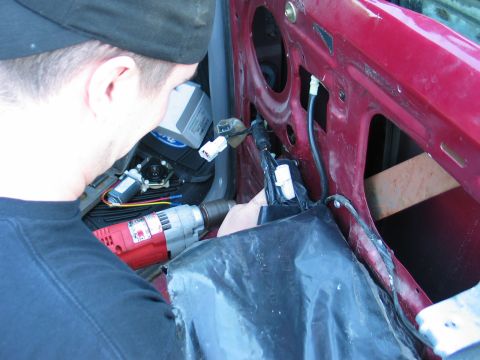 1995 Ford Bronco - A person works on the interior of a red car door, accessing window motor components and wiring.
