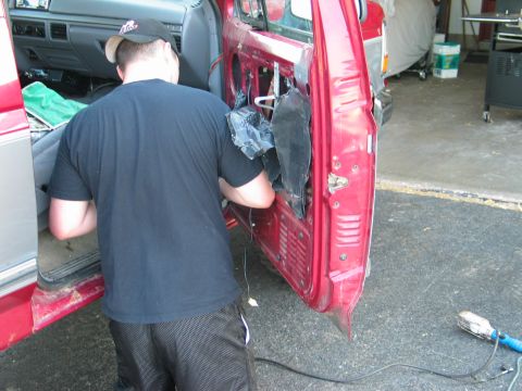 1995 Ford Bronco - A person is working on the interior of a vehicle door, likely for repairs or maintenance.