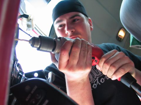 1995 Ford Bronco - A person works on the interior of a vehicle with a red and black drill.
