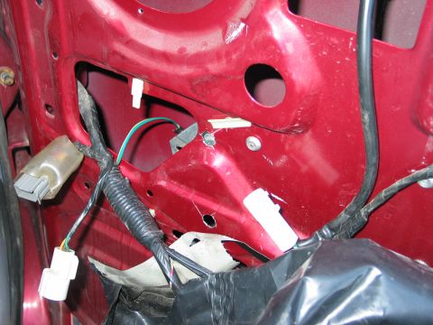 1995 Ford Bronco - Close-up of a red car door's interior showing wiring harnesses and connectors, with some metal structure exposed.
