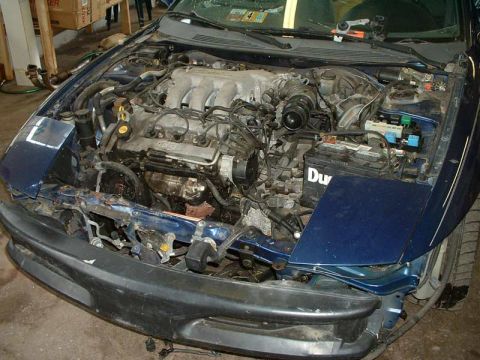 1994 Ford Probe - The engine compartment of a blue car is visible with the hood open, revealing the engine and battery.