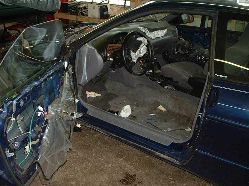 Blue car interior with door removed, showing dismantled dashboard and exposed wiring
