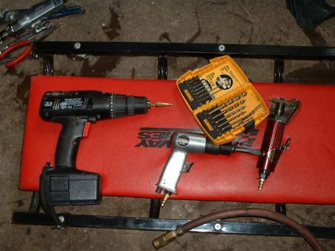 1994 Ford Probe - A collection of power tools including a cordless drill, air hammer, and a set of drill bits are laid out on a creeper.