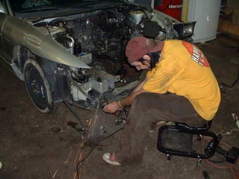 1994 Ford Probe - A man works on the engine of a silver car that has had its front end removed.