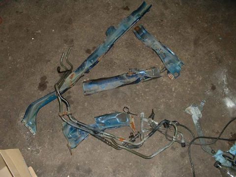 1994 Ford Probe - Disassembled car parts, including frame sections and fuel lines, lie on a garage floor.