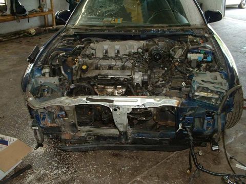1994 Ford Probe - The front of the car has been disassembled, exposing the engine and surrounding mechanical parts.