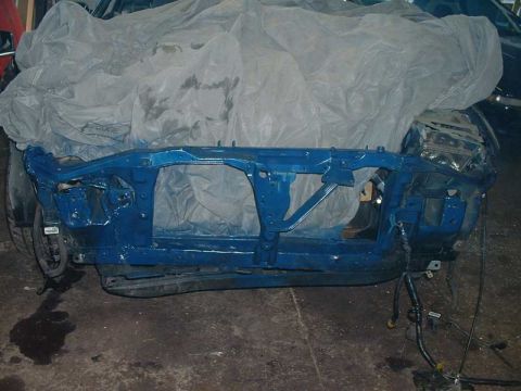 1994 Ford Probe - A car frame, painted blue, is partially covered by a grey tarp in a workshop.