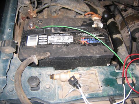 1994 Ford Bronco - A fuel injector and battery are visible in the engine bay of a vehicle.