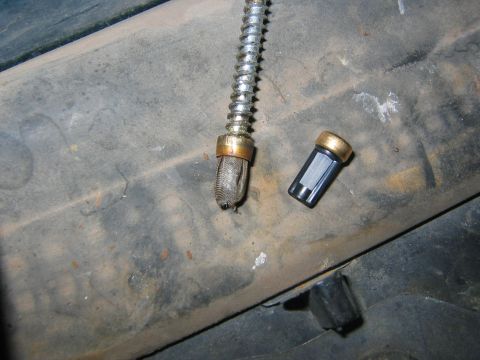 1994 Ford Bronco - A close-up shows a fuel filter screen and a detached cap, likely from a vehicle's fuel system.