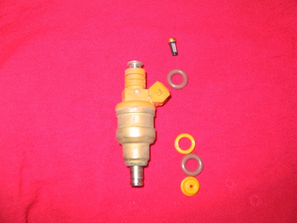 Fuel injector and O-rings on a red background. A small filter is also visible