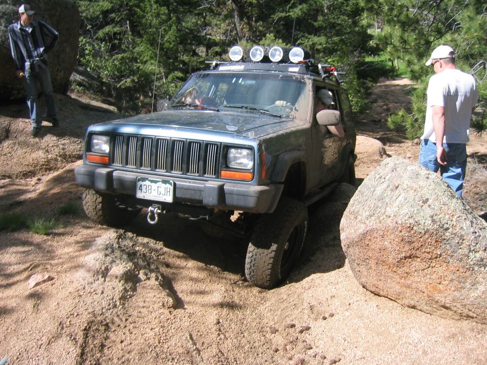 1997 Jeep Cherokee navigating a rocky trail with people watching