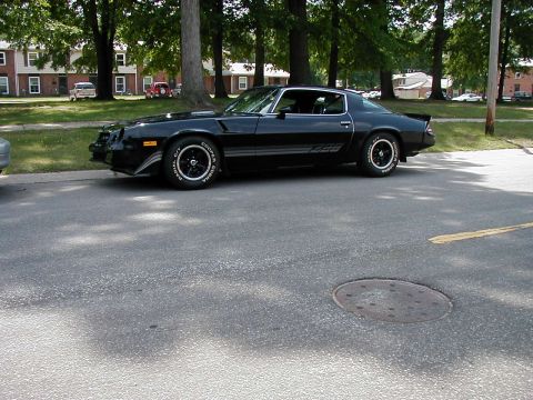 1997 Ford Taurus - A black Z28 coupe is parked on the side of a road with trees and buildings in the background.